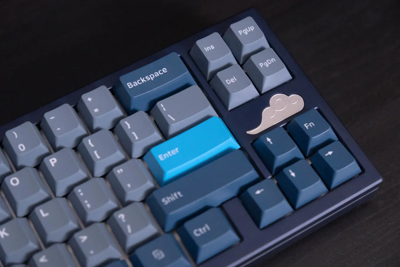 Close-up of the Aozora's blue keycaps, cyan enter key, and brass cloud badge.